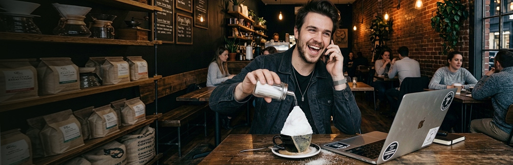Man pouring sugar into coffee cup in Coffee Shop
